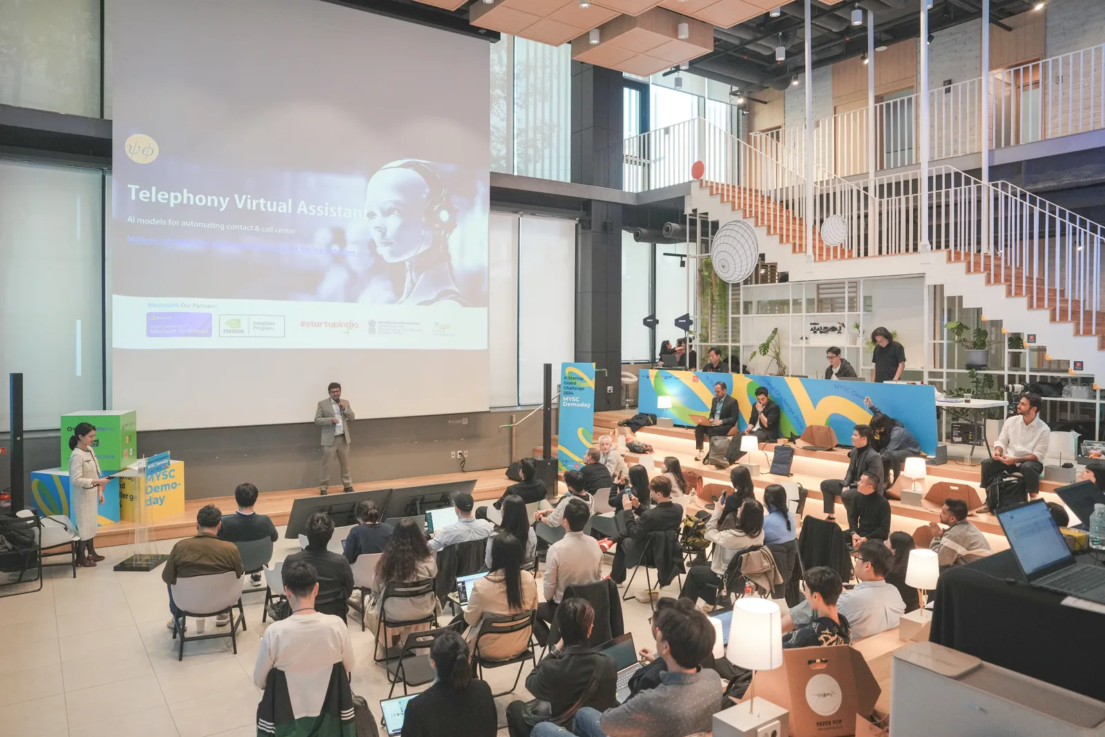 2024 K-Startup Grand Challenge 데모데이에서 스타트업 발표자와 발표 화면, 심사석·객석이 함께 보이는 피칭 현장